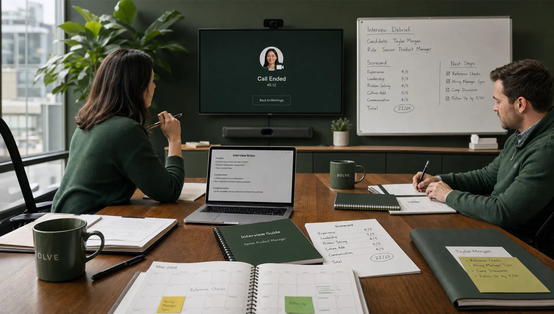 A wide scene in a modern office showing a recruiter and hiring manager in a live interview debrief, with a video call ending on a monitor facing the camera, handwritten scorecards, interview notes, and a calendar open on the table. The composition should emphasize the workflow around the interview rather than the interview itself, with a calm, organized atmosphere and clear evidence of decision-making and follow-up steps.
